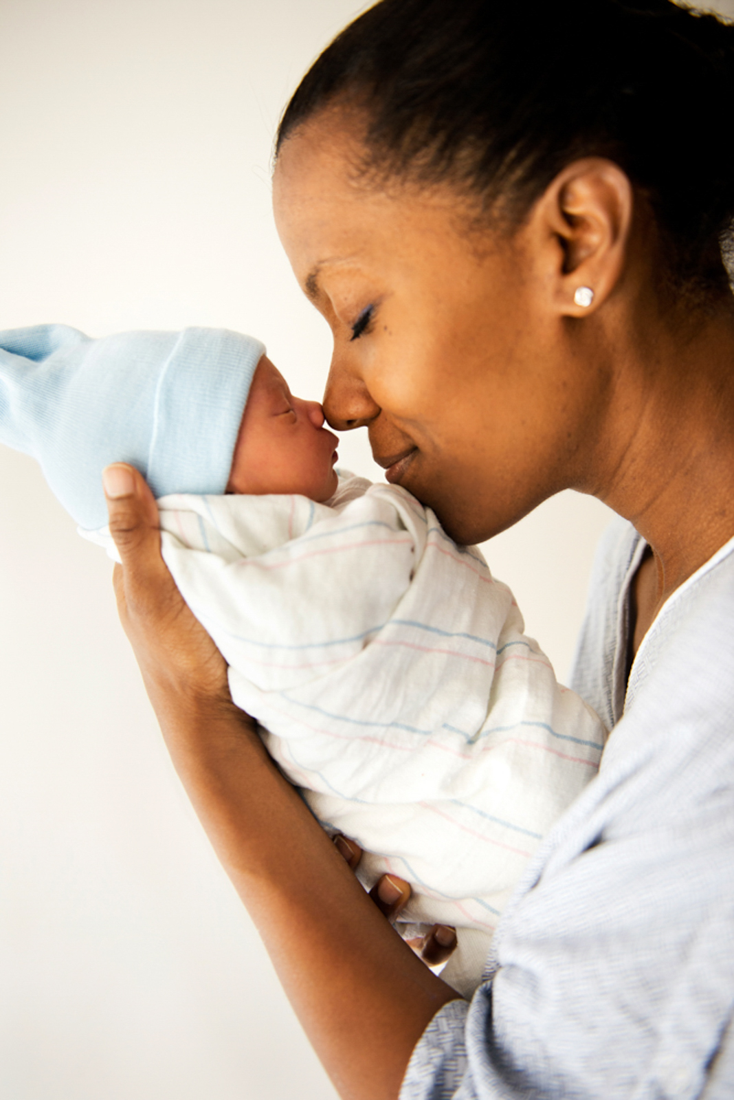 Portrait of mother holding newborn touching noses lovingly