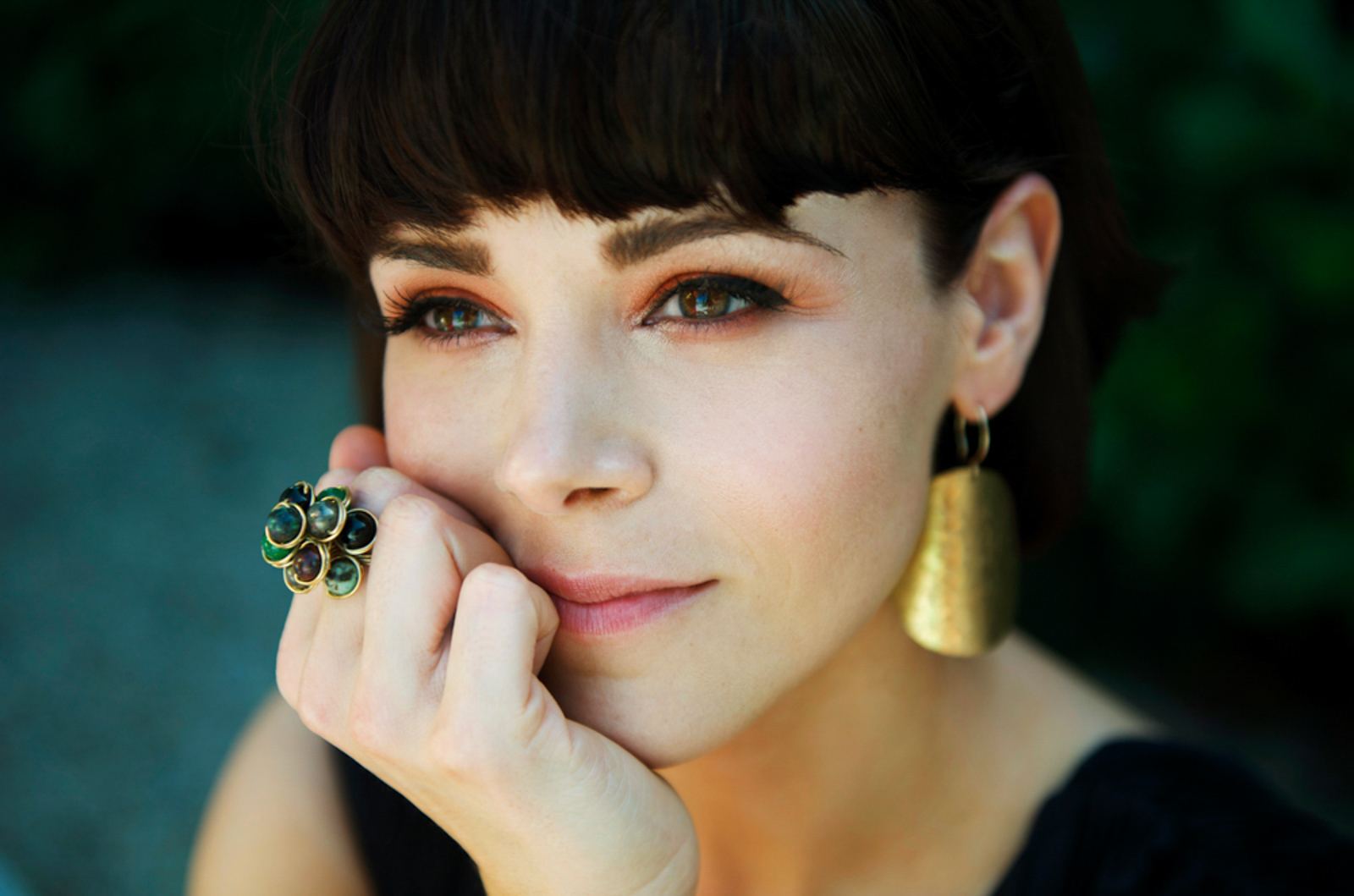 Portrait of woman with earrings and flower ring looking pensive