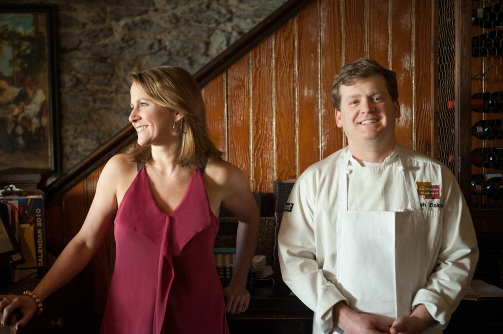 Portrait of a woman in a dress looking to the side and a man with a chef uniform smiling
