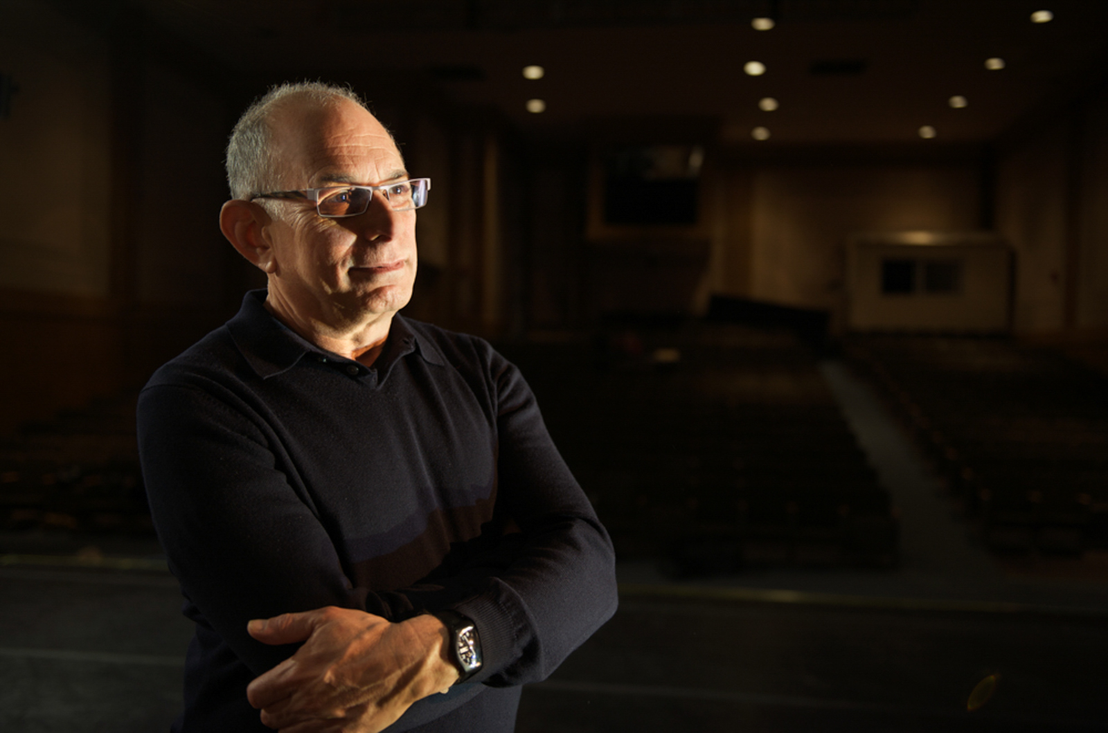 Environmental portrait of man with arms crossed in auditorium