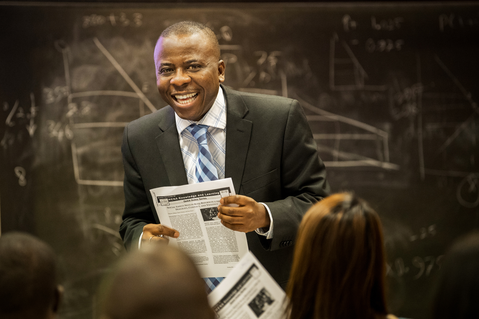 Instructor smiling in class in front of blackboard