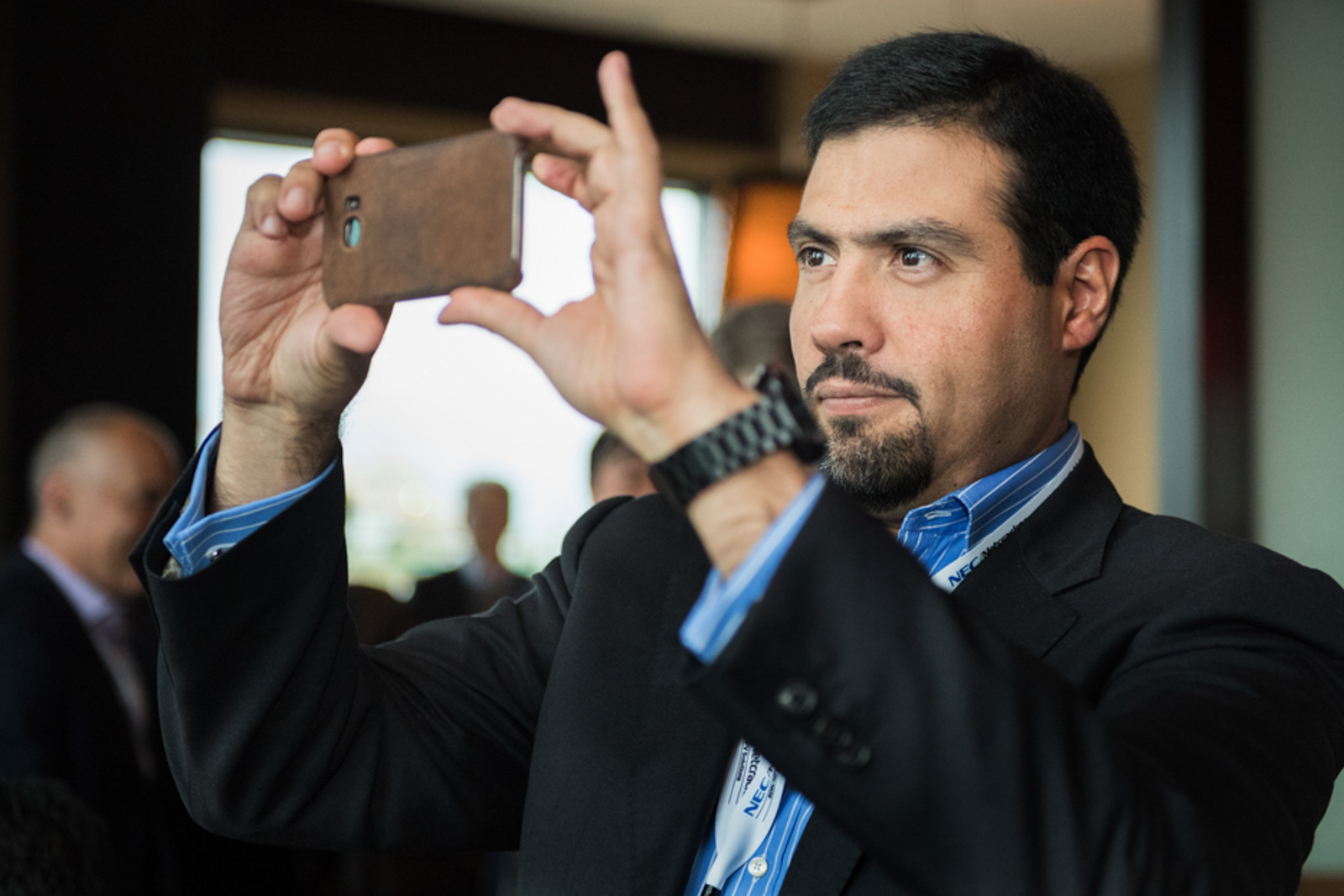 Candid image of man in a business gathering taking a cellphone photo