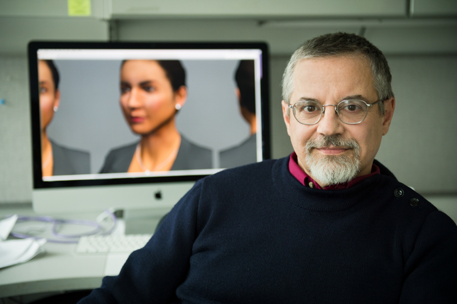 Portrait of professor with his work shown in a computer in the background