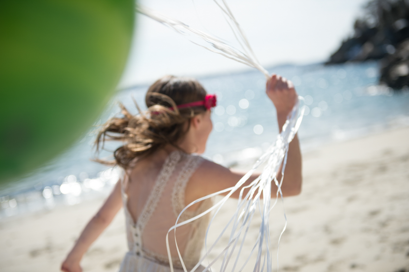 Portrait of child running at the beach holding balloons
