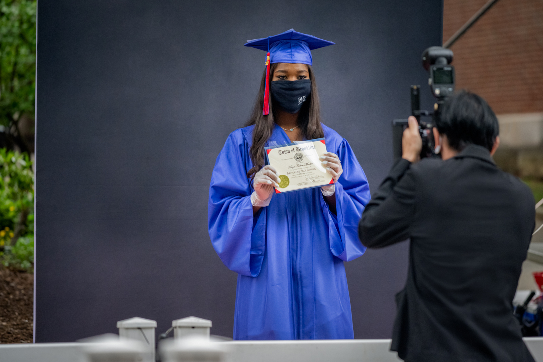high school graduate in mask being photographed outside