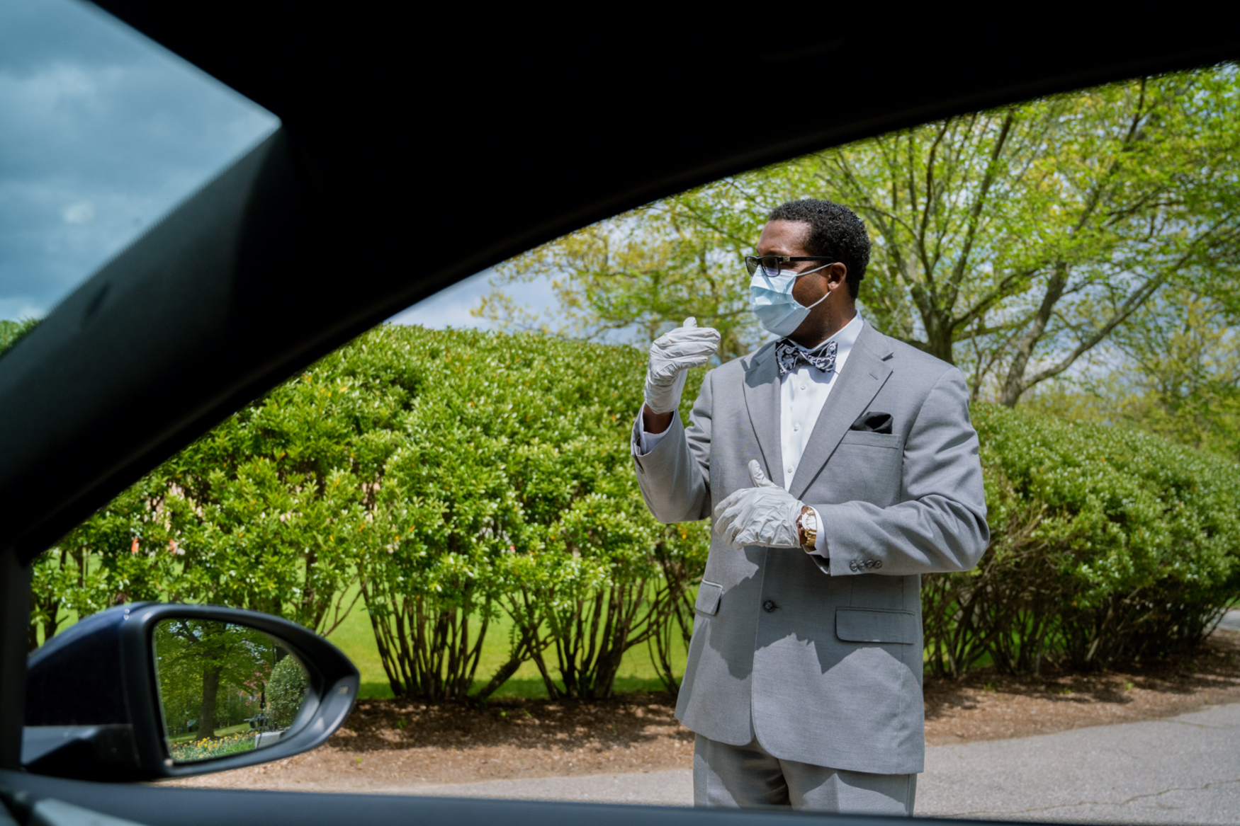 man in suit mask and gloves through car window