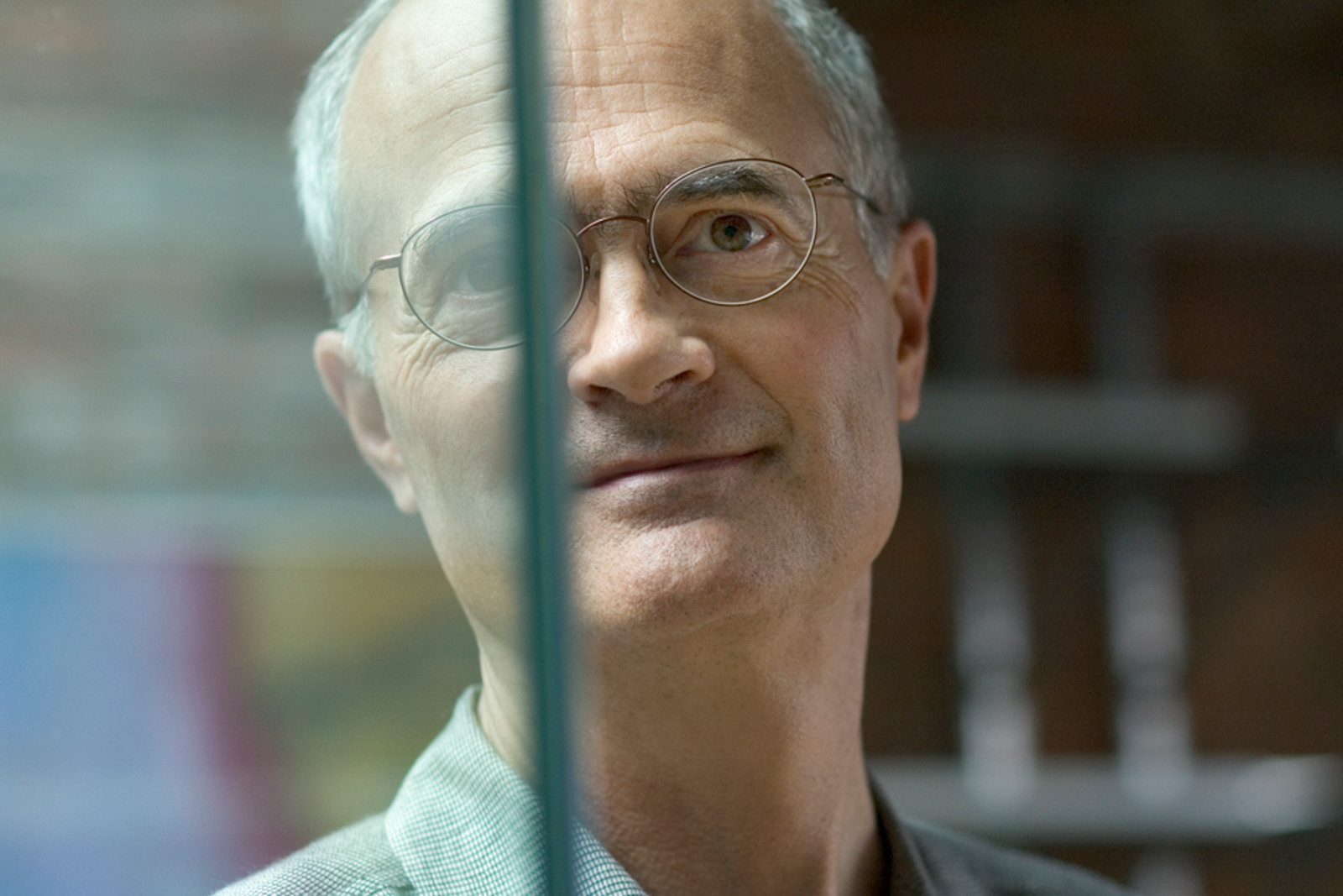 Portrait of older man looking pensive seen through glass