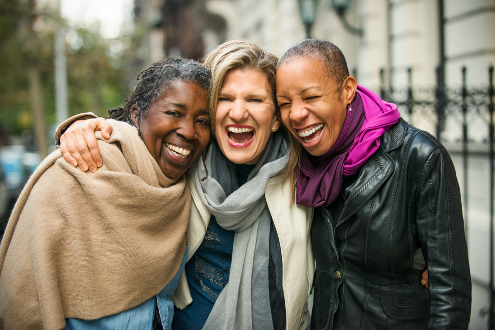 Three women hugging and smiling in a New York City street