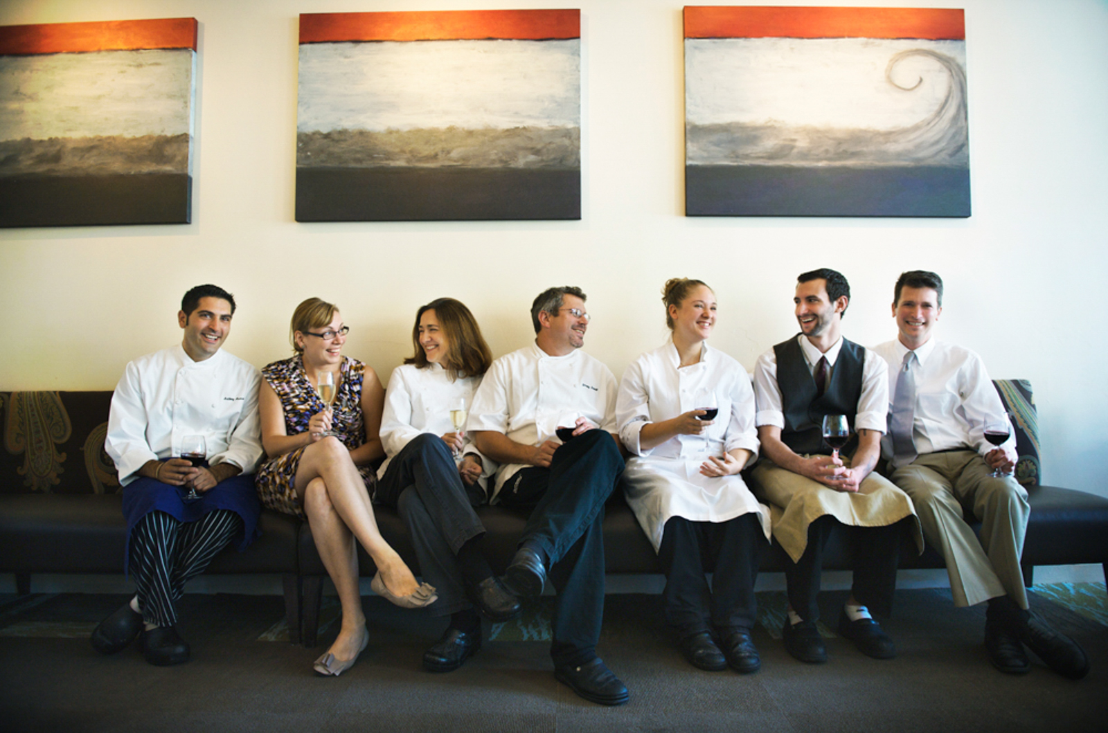 Group of chefs sitting in a couch smiling with artwork
