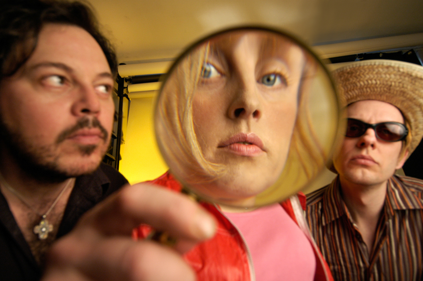 Portrait of band with a man holding a magnifying glass in front of a woman's face